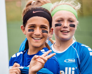 girls smiling holding peace sign at rush fest